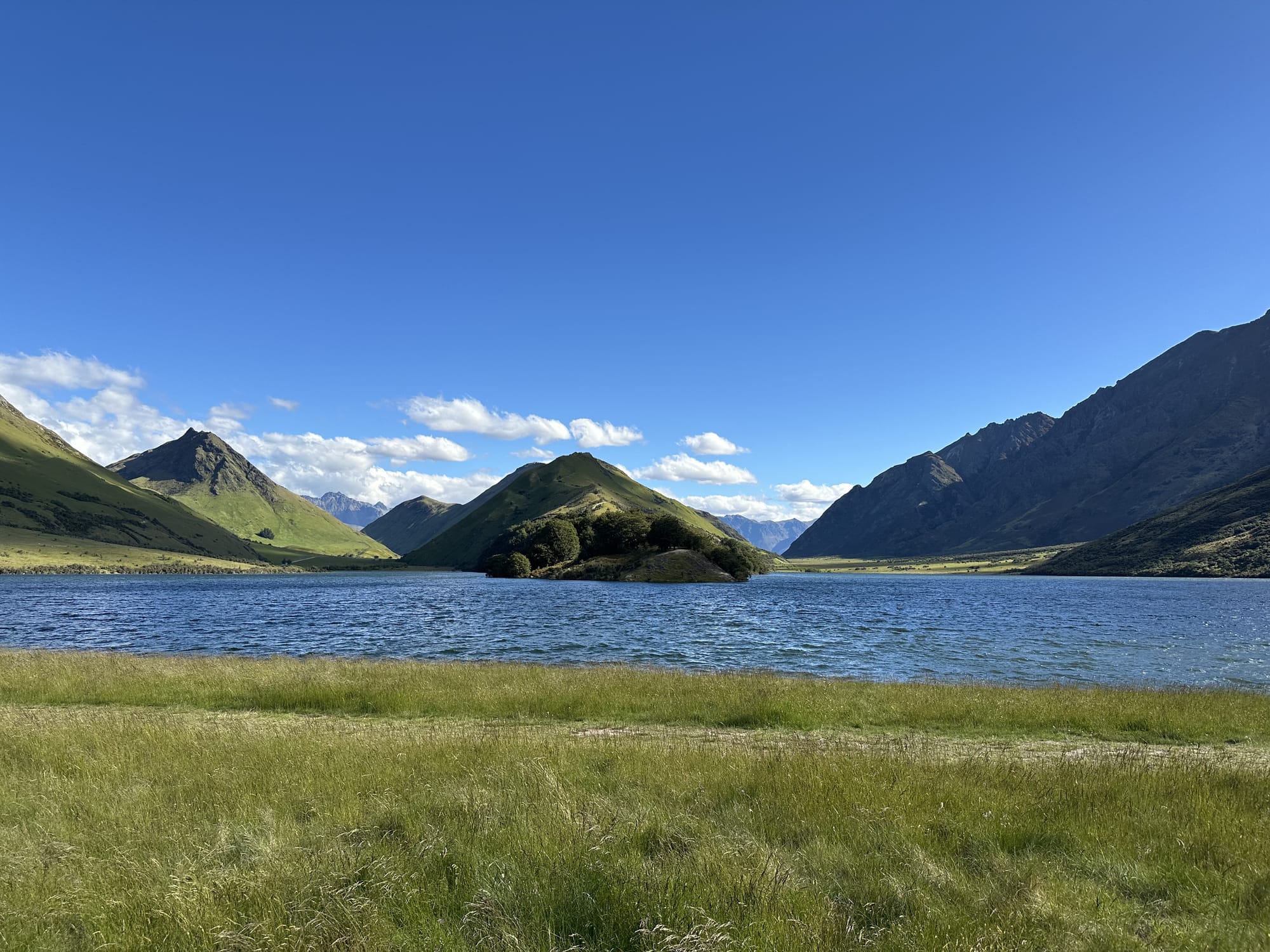 Grassy but steep peaks surround a blue lake in the centre